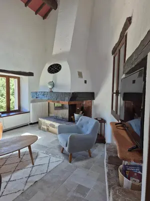 a living room with a fireplace and a chair at Gîte rural 8 à 10 personnes au coeur du Parc National du Haut Languedoc in Saint-Pons-de-Thomières