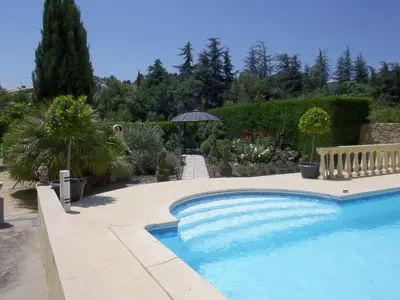 a swimming pool in a garden with an umbrella at Villa Angel - SPA in Caunes-Minervois