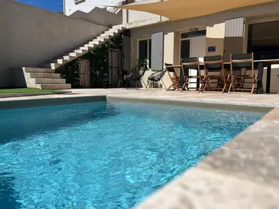 a swimming pool with chairs and a table next to a house at La Gruissanaise in Gruissan
