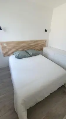 a white bed with two pillows on top of it at La Gruissanaise in Gruissan