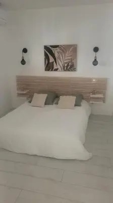 a white bed in a white room with two lights at La Gruissanaise in Gruissan