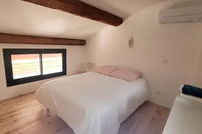a bedroom with a white bed and a window at La Gruissanaise in Gruissan