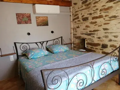 a bedroom with a bed in a stone wall at Gîte des Orangers in Roquebrun