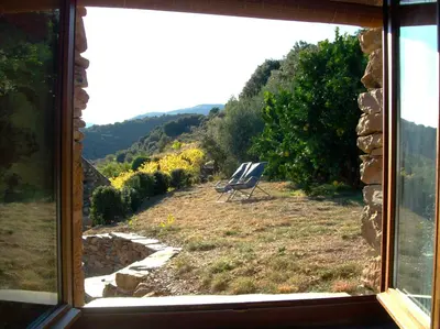 a view from a window of a chair in a field at Gîte des Orangers in Roquebrun