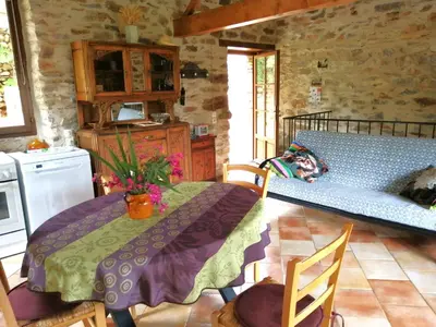a kitchen with a table and a bed in a room at Gîte des Orangers in Roquebrun