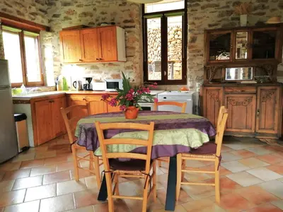 a kitchen with a table and some chairs and a table and a kitchen at Gîte des Orangers in Roquebrun