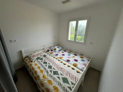 a small bedroom with a bed with a comforter and a window at La Gourgotte in Ajac
