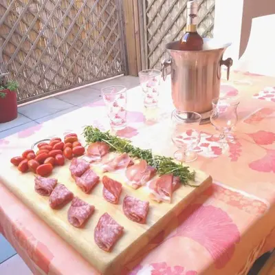 a cutting board with meat and tomatoes on a table at Appartement du bonheur- 6 personnes in Gruissan