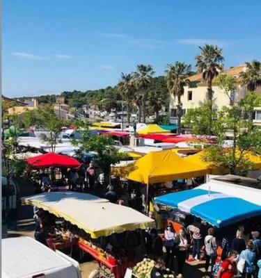 a crowd of people standing in a market with umbrellas at Appartement du bonheur- 6 personnes in Gruissan