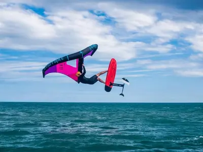 a person in the air on a surfboard in the ocean at Appartement du bonheur- 6 personnes in Gruissan