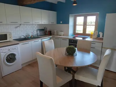 a kitchen with a wooden table and a table and chairs at Maison indépendante à la ferme in Palleville