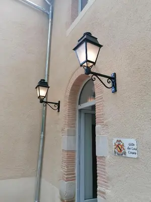 two lights on the side of a building with a door at Gîte de Las Cases 4 à 6 personnes in Lempaut