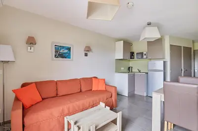 a living room with a couch and a kitchen at Résidence Odalys Côté Canal in Sallèles-dʼAude