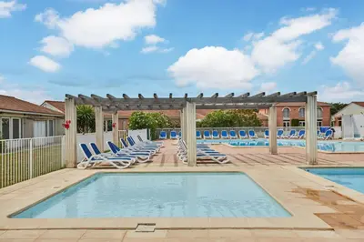 a swimming pool with lounge chairs and a pergola at Résidence Odalys Côté Canal in Sallèles-dʼAude