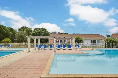 a swimming pool with blue chairs at Résidence Odalys Côté Canal in Sallèles-dʼAude