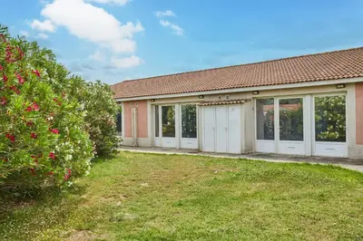 a building with white doors and a yard at Résidence Odalys Côté Canal in Sallèles-dʼAude