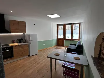 a kitchen and a living room with a table and a refrigerator at Studio les Rosiers in Quillan