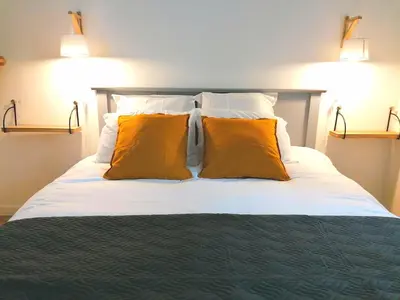 a bedroom with a bed with two orange pillows at Gîte des Cisterciens 7 à 9 personnes in Lempaut
