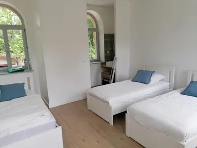 two beds in a room with two windows at Gîte des Cisterciens 7 à 9 personnes in Lempaut