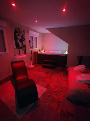 a living room with red lighting and a tub at La parenthèse Love room in Moussan