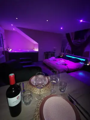 a table with a bottle of wine and wine glasses at La parenthèse Love room in Moussan