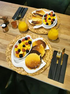 two plates of food on a table with pancakes and fruit at La parenthèse Love room in Moussan