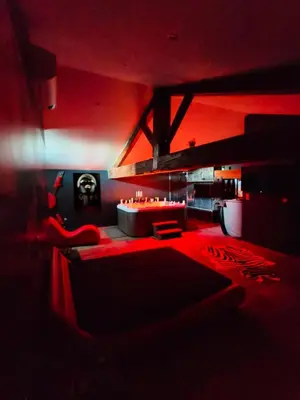 a red room with a couch and a table at La parenthèse Love room in Moussan