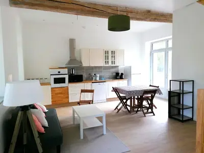 a kitchen with white cabinets and a table and chairs at Gîte des Cathares 2 personnes in Lempaut