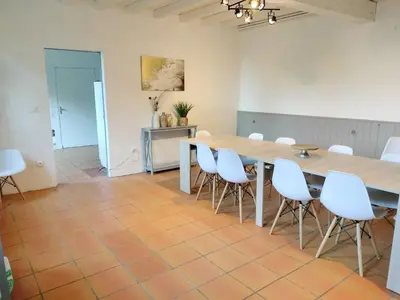 a dining room with a table and white chairs at L'Orangerie 14 personnes in Lempaut
