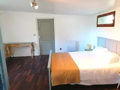 a bedroom with a large bed and a desk at L'Appartement de l'Orangerie in Lempaut