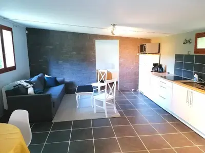 a kitchen and a living room with a couch and a table at L'Appartement de l'Orangerie in Lempaut