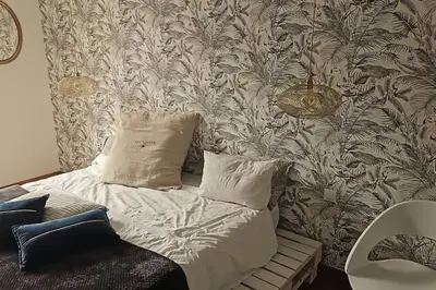 a bed with two pillows in a room with a wallpaper at Hébergement - Canal du midi in Saint-Martin-Lalande