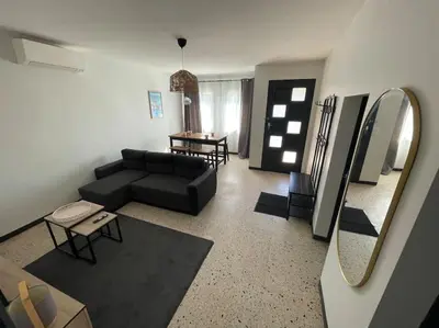 a living room with a black couch and a mirror at Maison 2 chambres 3 lits 4 couchages et extérieur in Villefranche-de-Lauragais