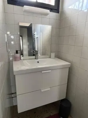 a white bathroom with a sink and a mirror at Maison 2 chambres 3 lits 4 couchages et extérieur in Villefranche-de-Lauragais
