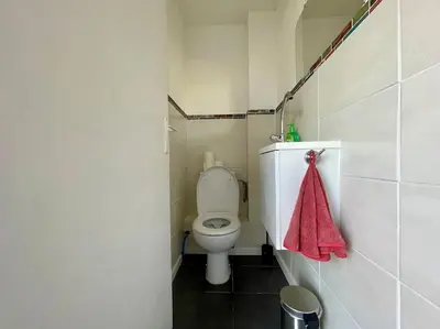 a bathroom with a toilet and a red towel at Maison Les Bruyères - 3 chambres - jardin et parking à Carcassonne in Carcassonne
