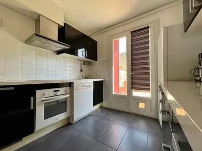 a kitchen with black and white appliances and a window at Maison Les Bruyères - 3 chambres - jardin et parking à Carcassonne in Carcassonne