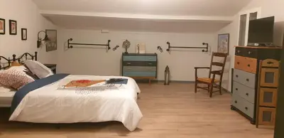 a bedroom with a bed with a dresser and a chair at LA PETITE BICOQUE au fond du jardin in Quillan