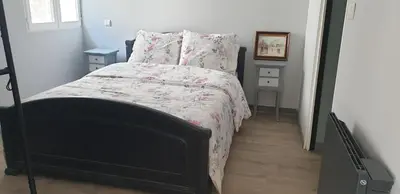 a bedroom with a bed with a white and pink comforter at LA PETITE BICOQUE au fond du jardin in Quillan