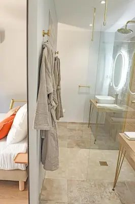 a bathroom with a glass door with a bed and a sink at Les Gîtes de Laure - L'Eden Romantique, B&B, Spa privatif et Petit Déjeuner, Couloir de nage, 10mn Carcassonne in Malves-en-Minervois