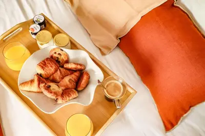 a tray of food on a bed with a plate of food at Les Gîtes de Laure - L'Eden Romantique, B&B, Spa privatif et Petit Déjeuner, Couloir de nage, 10mn Carcassonne in Malves-en-Minervois