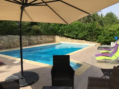 a swimming pool with an umbrella and chairs next to it at Superbe villa 4 ch climatisées avec piscine privée in Roquetaillade