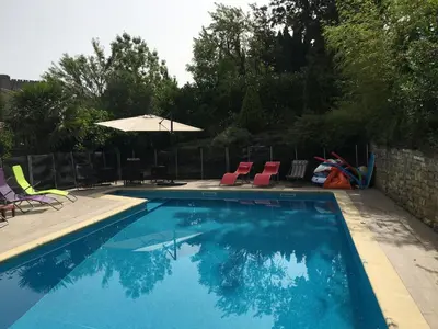 a swimming pool with chairs and an umbrella at Superbe villa 4 ch climatisées avec piscine privée in Roquetaillade
