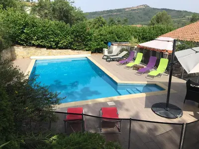 a swimming pool with lounge chairs and an umbrella at Superbe villa 4 ch climatisées avec piscine privée in Roquetaillade