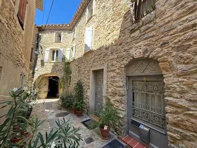 a stone building with a door and some plants at La Barbacane de Cascastel-des-Corbières in Cascastel-des-Corbières