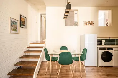 a dining room with a table and green chairs at Appart BonaVita Narbona in Narbonne