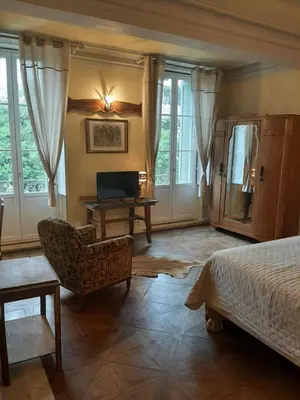 a bedroom with a bed and a desk and windows at Chambre Art Déco in Moux