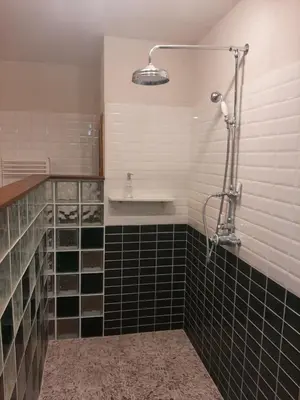 a bathroom with black and white tiles and a shower at Chambre Art Déco in Moux