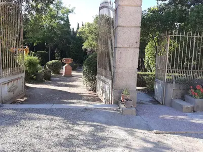 an entrance to a garden with a fence and plants at Chambre Art Déco in Moux