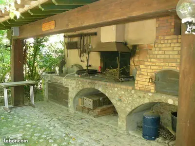 a large outdoor kitchen with a stone fireplace at Chambre Art Déco in Moux