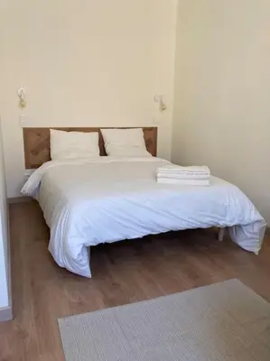 a bedroom with a white bed with white sheets and pillows at Hyper centre - Ecusson in Castres